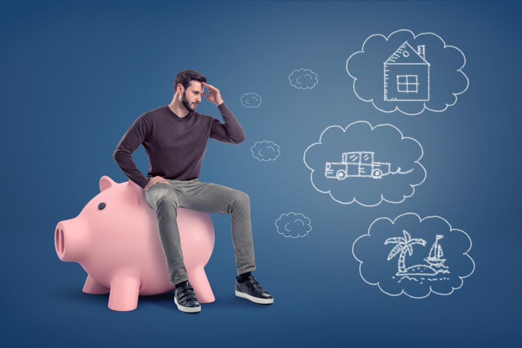 A thoughtful man sits on a large piggy bank