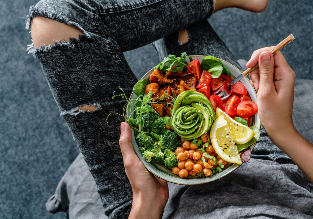 Woman in jeans holding Buddha bowl